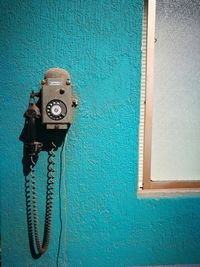 Close-up of old telephone on blue wall