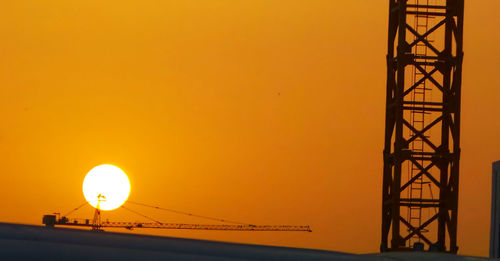 Silhouette illuminated lamp against orange sky