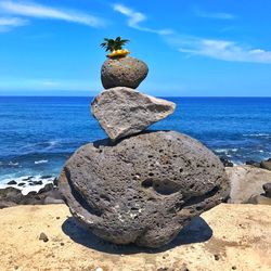 Rock on beach against sky