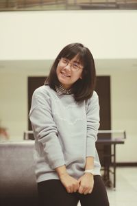 Portrait of smiling young woman standing against wall