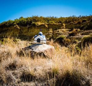 Traditional windmill on field against clear blue sky