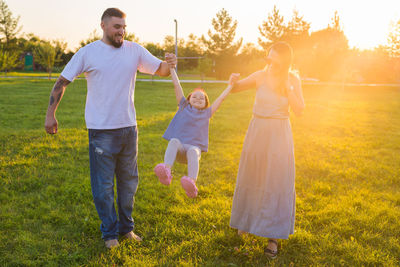 Rear view of friends standing on grass against plants