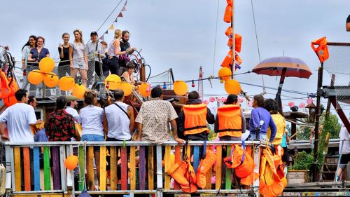 Rear view of people standing by railing against sky