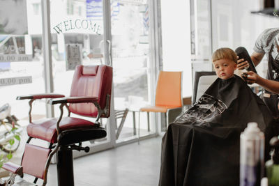 Barber giving haircut to adorable boy