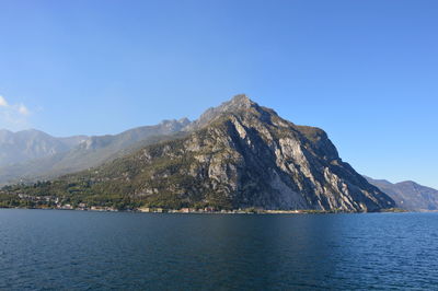 Scenic view of lake and mountains against clear blue sky