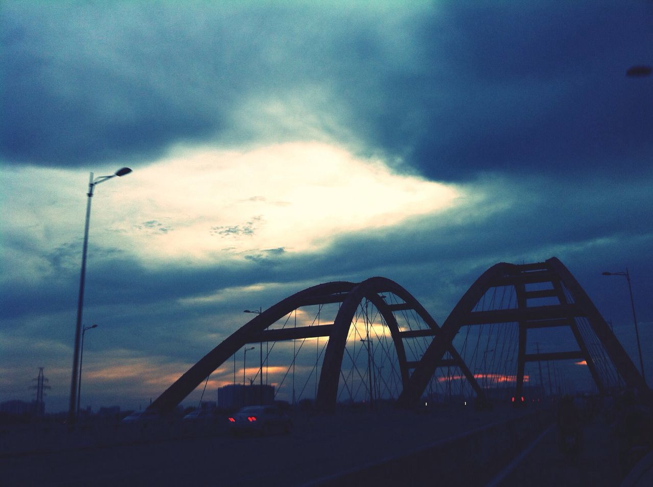 sky, cloud - sky, transportation, mode of transport, cloudy, land vehicle, silhouette, cloud, sunset, dusk, car, street light, weather, overcast, dramatic sky, low angle view, stationary, outdoors, bicycle, street