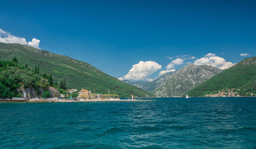 Scenic view of sea and mountains against blue sky