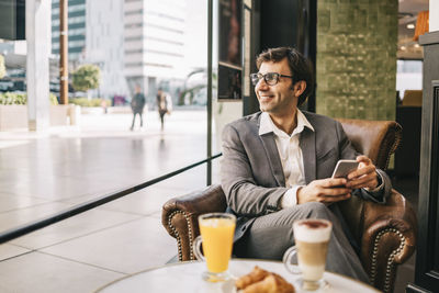 Young man using mobile phone while sitting on table