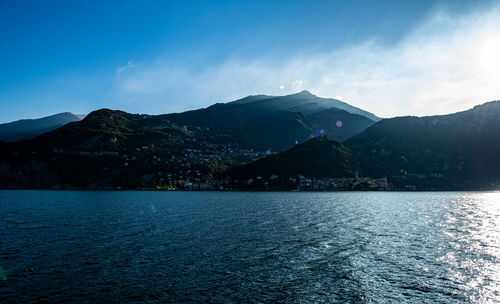 Scenic view of lake and mountains against blue sky