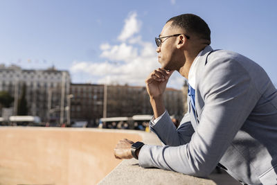 Businessman wearing sunglasses leaning on wall