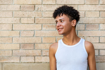 Smiling young man standing against brick wall