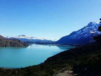 Scenic view of sea and mountains against clear blue sky