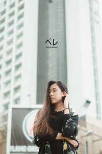 Portrait of woman standing against wall in city