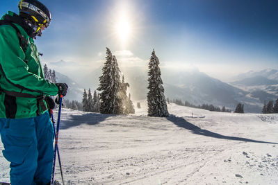 Side view of skier standing on snow covered field