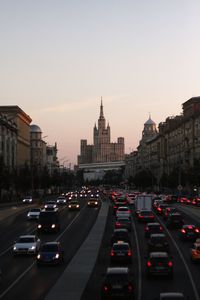 Traffic on road in city against sky during sunset