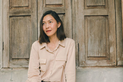 Portrait of woman standing against door