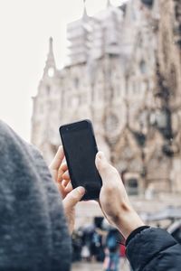 Midsection of man using mobile phone in city