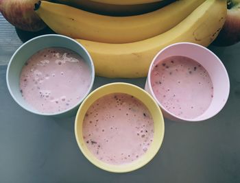 High angle view of fruit smoothies and bananas on table