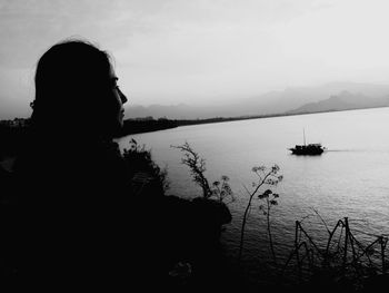 Silhouette woman looking at lake against sky