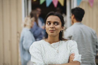 Thoughtful young woman with arms crossed during dinner party at cafe