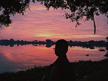 Silhouette of man in lake against sky during sunset