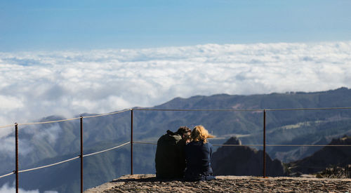 Rear view of couple sitting on mountain