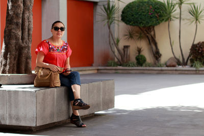 Full length portrait of woman sitting outdoors