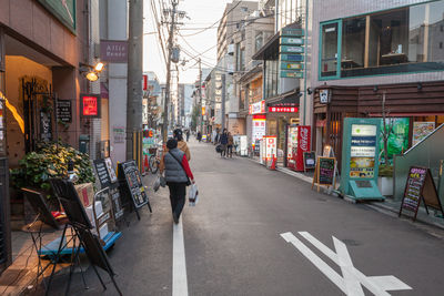 People walking on street amidst buildings in city