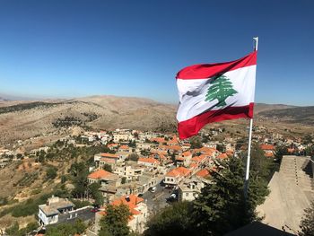 Flag against buildings in city against clear blue sky