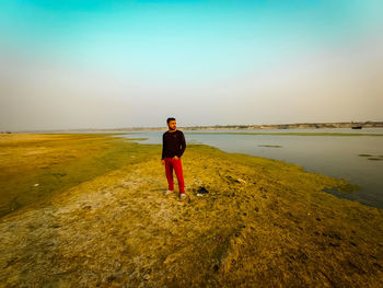 Rear view of man standing on beach against sky