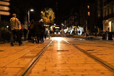 Rear view of people walking on illuminated street at night