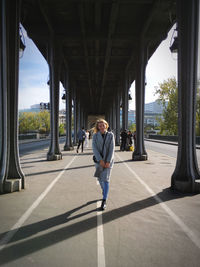 Full length of woman standing under bridge in city
