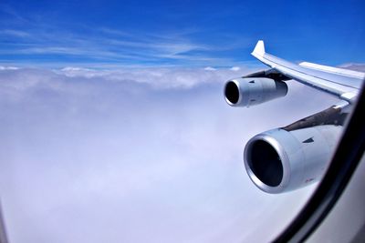 Airplane flying over clouds against blue sky