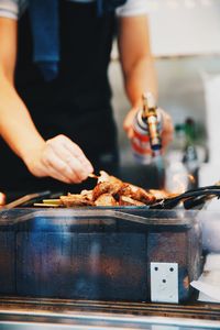 Midsection of man preparing food on barbecue grill