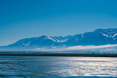 Scenic view of snowcapped mountains against blue sky