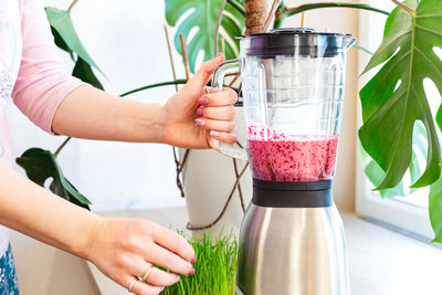 A woman mixes a delicious almond milk, berry and herbs smoothie in a blender. smoothie diet. 