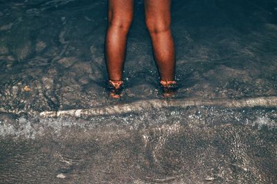 Low section of person standing in water