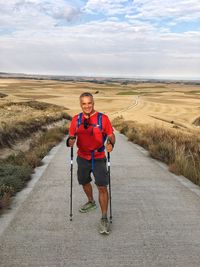 Full length portrait of happy man standing on pathway on field