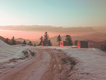 Road on a snowy mountain against sky during sunset