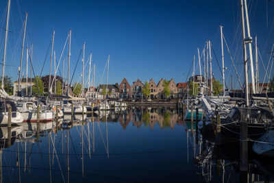 Sailboats moored at harbor against clear blue sky