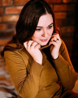 Beautiful young woman looking away while sitting at home