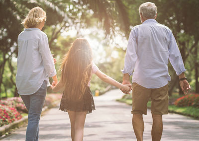 Rear view of girl with grandparents walking on road