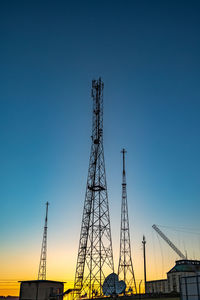 Low angle view of silhouette cranes against clear sky