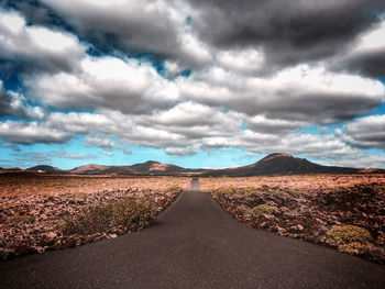 Empty road amidst landscape against sky