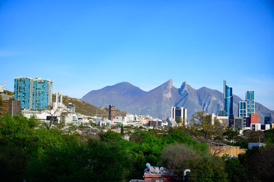 Buildings in city against blue sky