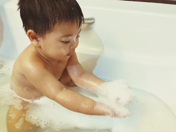 Shirtless boy taking bath in bathtub