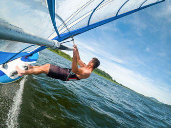 Wide-angle shot of adult man windsurfing on lake wallersee, austria.