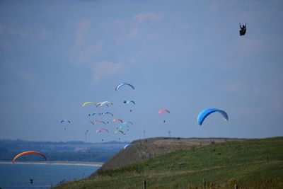 Hot air balloons flying over land against sky