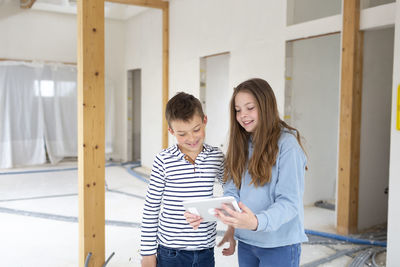 Sister sharing smart phone with brother at home