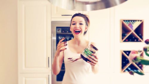 Portrait of happy woman holding chocolate container in kitchen at home